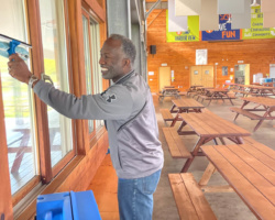 Volunteer cleaning the glass windows on the island before the 2021 camp season